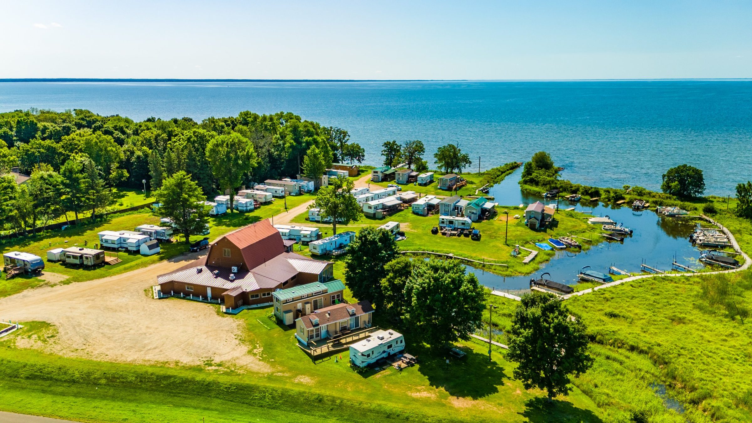 Aerial view of Mudflats Bar & Grill at Barnacles Resort: the red-roofed building, the resort, the boat harbor, and Lake Mille Lacs stretching to the horizon