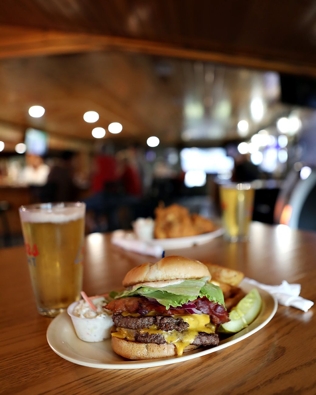 A bacon cheeseburger with coleslaw and a pickle on the Mudflats bar